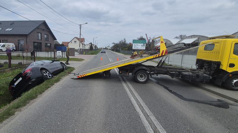 Laweta Prusakowski z opuszczoną platformą przy samochodzie, który po kolizji zjechał do rowu